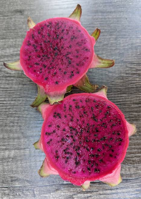 Owner-supplied Japanese Godzilla photograph: two magenta dragon-fruit halves on grey wood